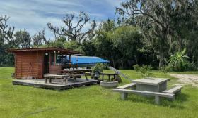 A shack with picnic tables and outdoor essentials