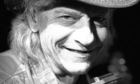 Singer songwriter bluesman Denny Blue closeup in a fedora, smiling