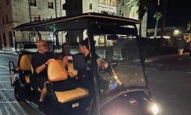 A tour guide hosts two guests while touring St. Augustine in an EV at night