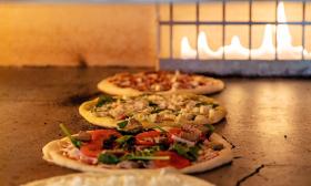 Pizzas getting baked in the wood-fired oven