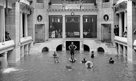 The Alcazar pool during the Gilded Age, with men exercising in the pool and people watching from the balcony