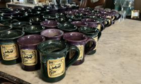 Branded coffee mugs in plum and green on the counter at Carriage Way Bed and Breakfast 