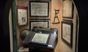 A display of pirate maps on the wall and on a captain's standing desk