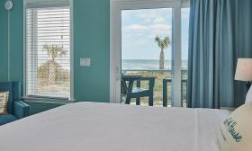 This soft green hotel bedroom has a deck with a view of the beach and Atlantic Ocean