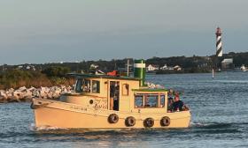 The boat from Tiny Tug Tours steaming past the St. Augustine Lighthouse