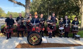 A group of Jacksonville firefighters in kilts stand together with bagpipes and drums