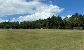 A soccer field with nets and bleachers on the outskirts