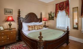 This bedroom has a unque carved wooden bed, and formal furnishings