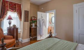 A view from the the bed shows a comfortable seat by the window and the door to the plush bath 