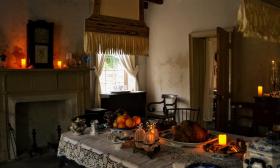 The darkened candlelit dining room decorated in the era of the 1800s during mourning