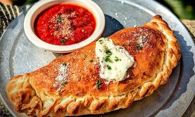 A calzone with a side of marinara sauce