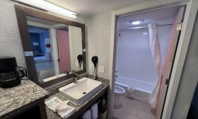 This hotel room has a sink and counter outside the more private bathroom