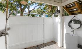 This fully-fenced outdoor shower has a sink and mirror