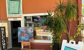 The entrance to Art Box Gallery, in a terra cotta building with art and a welcome sign