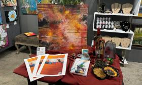 This gallery display shows painted art, jewelry, and a wooden display table