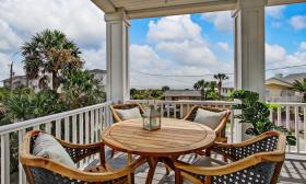 This second-story deck near the beach has a teak table and four matching chairs and a great view