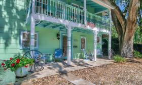 This carriage-house rental property is painted green and nestled among old oak trees