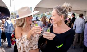 Two women toast each other at a food and drink festival