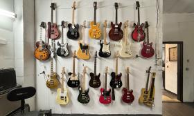 This white wall has rows of electric guitars of different types and colors