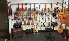 Ukeleles, banjos, mandolines, cover this wall at 5th Centruy Music