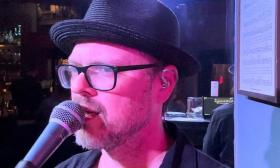 Matt Wilson in a hat, singing into a mic