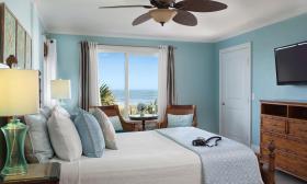 A blue and white bedroom with wood furnture and abundant pillows