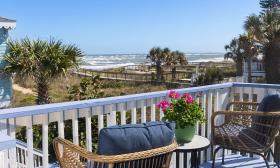 Two cozy arm chairs and a table with a pot of pink flowers with a view of the Atlantic