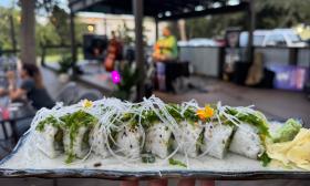 A sushi platter sitting in the forefront with a band performing on the stage