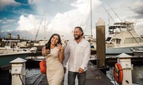 An engaged couple walking along a dock