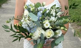 A bridal bouquet with soft blues, creamy roses and abundant greenery