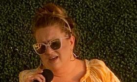 Vocalist Sarah Herforth in sunglasses, with micropone, singng