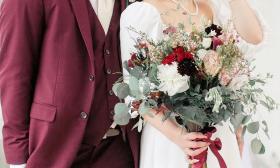 The torsos of a groom and bride showing the beautiful bouquet the bride is carrying