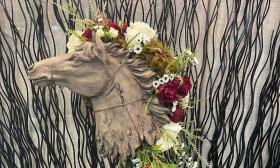 A floral arrangement on a statue of a horse's head