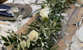 This table decor features a green-leaf runner with white roses