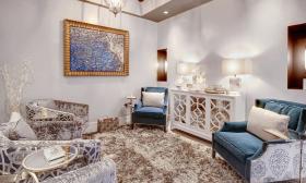 The waiting room at the Casa Monica Spa with soft chairs, a plush carpet, and teal accents