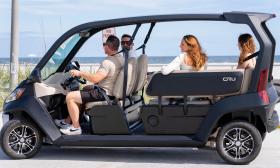 Customers riding by the beach in a golf cart