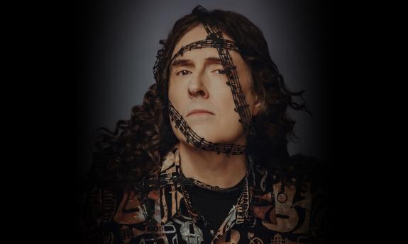 Weird Al Yankovic strikes a pose with music notes cascading across his face, set against a sleek black backdrop.