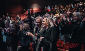 Two women standing an applauding in an audience at the St. Augustine Film Festival