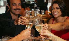 A couple raise their glasses with another couple over dinner