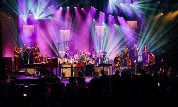 Bandmates from Tedeschi Trucks perform in front of a large audience.