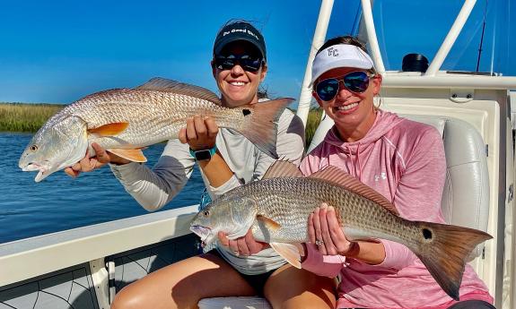 Two women lifting up redfish