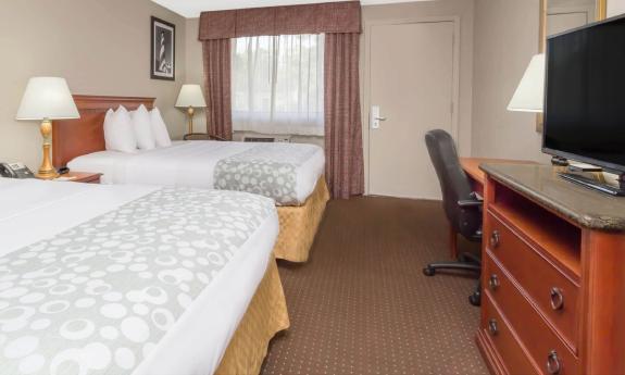 This hotel room has two queen beds, a chest of drawers, and a desk with desk chair