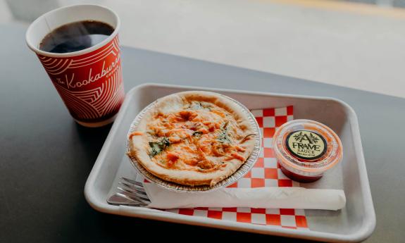 An Aussie pie with a hot cup of coffee on the side