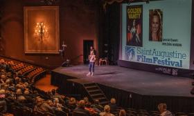 A woman on stage discussing a film to be presented at the St. Augustine Film Festival