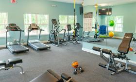 The fitness center at Sun Outdoors has multiple devices in a spacious green-painted room