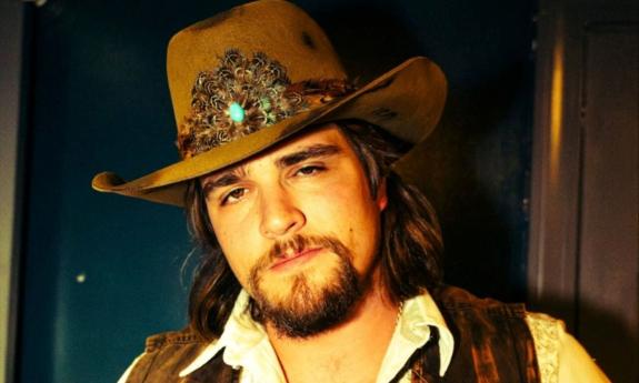 Gavin Adcock wears a brown cowboy hat and poses in front of a dark blue backdrop.