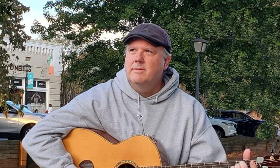 Songer songwriter Jimmy Bragg with guitar, outside