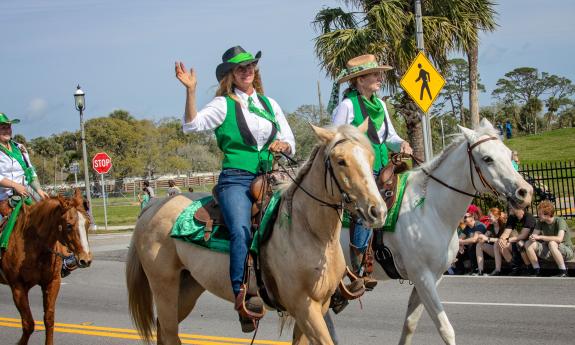 Horseback riders and their steeds decked out in bright green for the parade