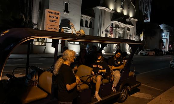 Three tour guides and ghost guards await guests in their golf cart