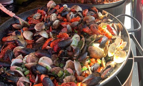 A large pan with a variety of seafood cooking with seasonings 